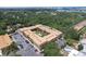 Aerial view showcases a condo complex with a landscaped courtyard, parking and lush trees with coastal views in the distance at 12760 Indian Rocks Rd # 579, Largo, FL 33774