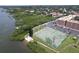 Overhead view of a waterfront tennis court adjacent to condo complex and lush greenery along the waterway at 12760 Indian Rocks Rd # 579, Largo, FL 33774