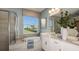 Luxury bathroom features a soaking tub, double vanity, and a large window with a view of the lush landscaping at 1797 Trailhead Ln, Zephyrhills, FL 33541