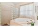 Spa bath with large tub, glass block partition, tile surround, and window with light-filtering curtains at 18502 Keystone Manor Rd, Odessa, FL 33556