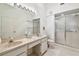 Bright bathroom featuring a double vanity, walk-in shower with glass door, and white tile floors at 2291 Americus W Blvd # 23, Clearwater, FL 33763