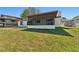 Exterior view of the home with a screened in lanai and green backyard at 3334 Pineview Dr, Holiday, FL 34691