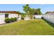 Expansive backyard with lush green lawn, white fencing, mature trees, and storage shed at 4532 W Idlewild Ave, Tampa, FL 33614