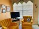 Bright living room features two mustard colored armchairs and a window with blinds at 4558 Blossom Blvd # D, Zephyrhills, FL 33542