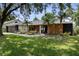 Inviting single-story home with manicured front yard, lovely landscaping, and a covered entrance with rocking chairs at 4715 Kemble Ct, Tampa, FL 33624