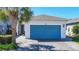 Charming single-story home featuring a blue garage door, paver driveway, and attractive landscaping with a palm tree at 5415 Los Robles Ct, Palmetto, FL 34221