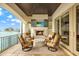 Covered outdoor patio with a fireplace, TV, and comfortable seating overlooking the water at 5630 Bayview Dr, Seminole, FL 33772