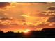 Beautiful sunset over a silhouetted neighborhood, featuring vibrant orange and yellow hues across the sky at 5630 Bayview Dr, Seminole, FL 33772