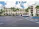 The exterior of the condo building features palm trees and parking lot with several parking spaces at 8800 Bay Pines Blvd # 318, St Petersburg, FL 33709