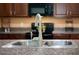 Close up view of kitchen sink and faucet with granite countertops, set against a backdrop of black appliances at 9736 Sage Creek Dr, Ruskin, FL 33573