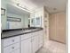 A bathroom with a spacious vanity featuring a black granite countertop and white cabinets and white tile floors at 1 Key Capri # 301E, Treasure Island, FL 33706