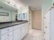 A bathroom with a spacious vanity featuring a black granite countertop and white cabinets and white tile floors at 1 Key Capri # 301E, Treasure Island, FL 33706