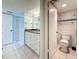 Bathroom featuring white cabinets, granite counters, and white tile floors, plus toilet and shower visible at 1 Key Capri # 301E, Treasure Island, FL 33706