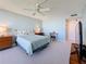 Bright bedroom with a queen bed, light blue walls, carpet floors, and a fan at 1 Key Capri # 301E, Treasure Island, FL 33706
