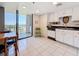 Bright condo kitchen with white cabinets, black countertops, and balcony access with water view at 1 Key Capri # 301E, Treasure Island, FL 33706