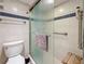 A white-tiled shower with blue accents features a frosted glass door and metal hardware with a built in seat at 1 Key Capri # 301E, Treasure Island, FL 33706