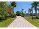 Paver driveway leading to the house surrounded by lush tropical landscaping and palm trees at 112 Gause Dr, Venice, FL 34293