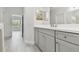 Bathroom features a vanity with grey cabinets, modern fixtures, and tile flooring at 12408 Palatka Dr, Venice, FL 34293