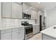 A modern kitchen with stainless steel appliances, gray cabinets, and white countertops at 12408 Palatka Dr, Venice, FL 34293