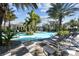 Resort-style pool with comfortable lounge chairs surrounded by lush, tropical landscaping under a sunny, blue sky at 12408 Palatka Dr, Venice, FL 34293
