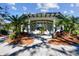 A beautiful outdoor lounge area with palm trees, stone columns, and white chairs sits by the community pool at 12408 Palatka Dr, Venice, FL 34293