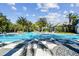 A large pool is bordered by lounge chairs and palm trees beneath a partly cloudy sky at 12408 Palatka Dr, Venice, FL 34293