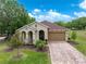 Charming single-story home with a brick driveway, a two-car garage and manicured lawn at 14198 Thoroughbred Dr, Dade City, FL 33525