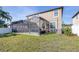 Backyard view showcases a screened-in patio, lush lawn, and well-maintained landscaping at 1564 Imperial Key Dr, Trinity, FL 34655