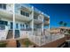 Three-story waterfront condo with white facade, balconies, stairs, and a fenced pool area with direct access to the water at 161 Brightwater Dr # 8, Clearwater Beach, FL 33767