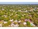 Aerial view of a home surrounded by lush trees, tennis courts, and a serene neighborhood landscape at 2644 2Nd Ct, Palm Harbor, FL 34684