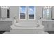 Bathroom featuring a soaking tub with dual sinks, marble accents, and natural light at 28355 Picana, Wesley Chapel, FL 33543