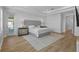 Main bedroom with hardwood floors, tray ceiling, a large bed, and modern nightstands at 28355 Picana, Wesley Chapel, FL 33543