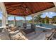 Inviting outdoor patio features a wood ceiling, comfortable seating, and a serene lake view with a pool nearby at 28355 Picana, Wesley Chapel, FL 33543