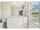 Bathroom with a double sink vanity, large mirror, and a window providing natural light at 35168 Arya Way, Zephyrhills, FL 33541