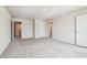 A bright room with neutral carpeting and multiple doorways, offering a versatile space at 35168 Arya Way, Zephyrhills, FL 33541