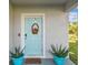 Close-up of a charming light blue front door adorned with a wreath and flanked by matching potted plants at 35168 Arya Way, Zephyrhills, FL 33541