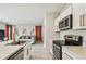 Modern kitchen with stainless steel appliances, white cabinets and gold hardware with view to living area at 35168 Arya Way, Zephyrhills, FL 33541