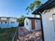 Building exterior with red brick walkway, orange door, privacy fence, and mature shade tree at 4119 W Nassau St, Tampa, FL 33607