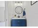 Modern bathroom featuring a blue vanity with gold hardware, round mirror, and stylish lighting fixtures above the sink at 4859 Napoli Ne Ct # 4859, St Petersburg, FL 33703