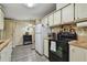 Functional kitchen featuring essential appliances, vintage-style cabinets, and durable laminate flooring at 5832 Sussex Dr, Tampa, FL 33615