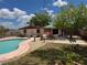 Backyard pool and patio with a privacy fence, a picnic table under an umbrella, and landscaping at 6420 N Thatcher Ave, Tampa, FL 33614