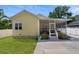 Yellow home with a screened in back porch, yard, and a concrete patio at 7701 N Dartmouth Ave, Tampa, FL 33604