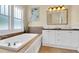 Well-lit bathroom with a soaking tub, double vanity with white cabinets, and a frosted window at 7701 N Dartmouth Ave, Tampa, FL 33604