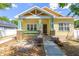 Charming yellow home featuring a covered porch with decorative stone pillars and a well-manicured lawn at 7701 N Dartmouth Ave, Tampa, FL 33604