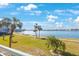 Scenic waterfront view with a green lawn, palm trees, and a sidewalk along the water at 8020 Sailboat Key S Blvd # 101, St Pete Beach, FL 33707