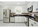 Modern kitchen with stainless steel appliances, granite countertops, white cabinets, and tile flooring at 8902 N Hamner Ave, Tampa, FL 33604