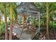 Relaxing outdoor common area offering a shady pergola with a swing and rocking chairs in lush tropical landscaping at 946 Highland Ave # 23, Dunedin, FL 34698