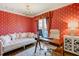 Stylish home office with bright red patterned wallpaper, a white sofa, and functional wooden desk space at 1102 Palm View Ave, Belleair, FL 33756