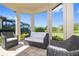 Relax in this covered outdoor living space featuring wicker furniture and serene views of the surrounding landscape at 11414 Juglans Dr, Odessa, FL 33556