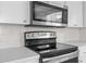 Features a black glass top stove and stainless steel microwave and white cabinets at 11422 Yellowwood Ln, Port Richey, FL 34668